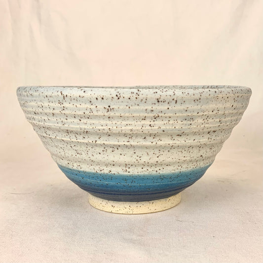 Ramen bowl with white speckled clay and two blue rings at the bottom, throwing lines from fingers as texture.