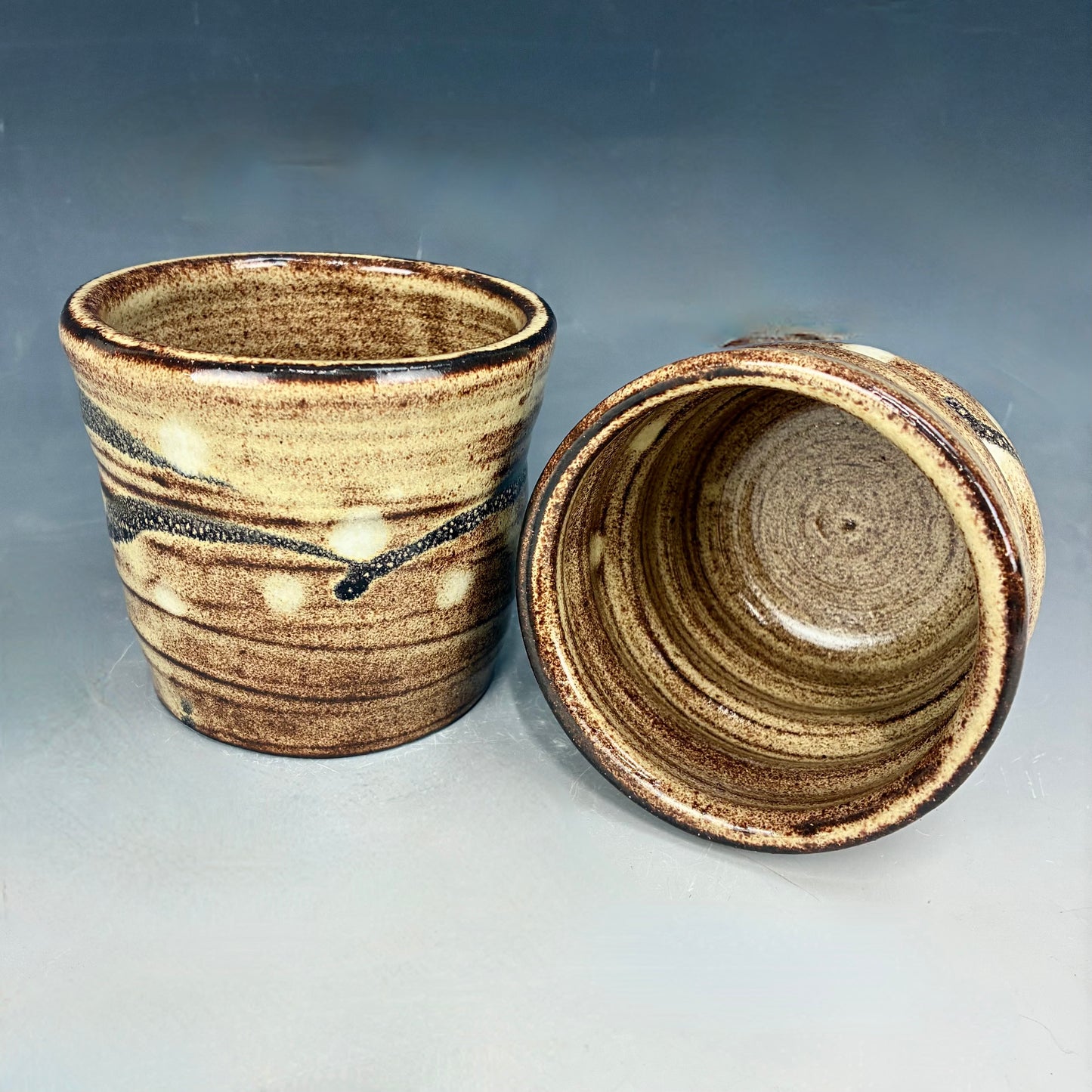Two ceramic pots with brown and beige glaze on a gray background