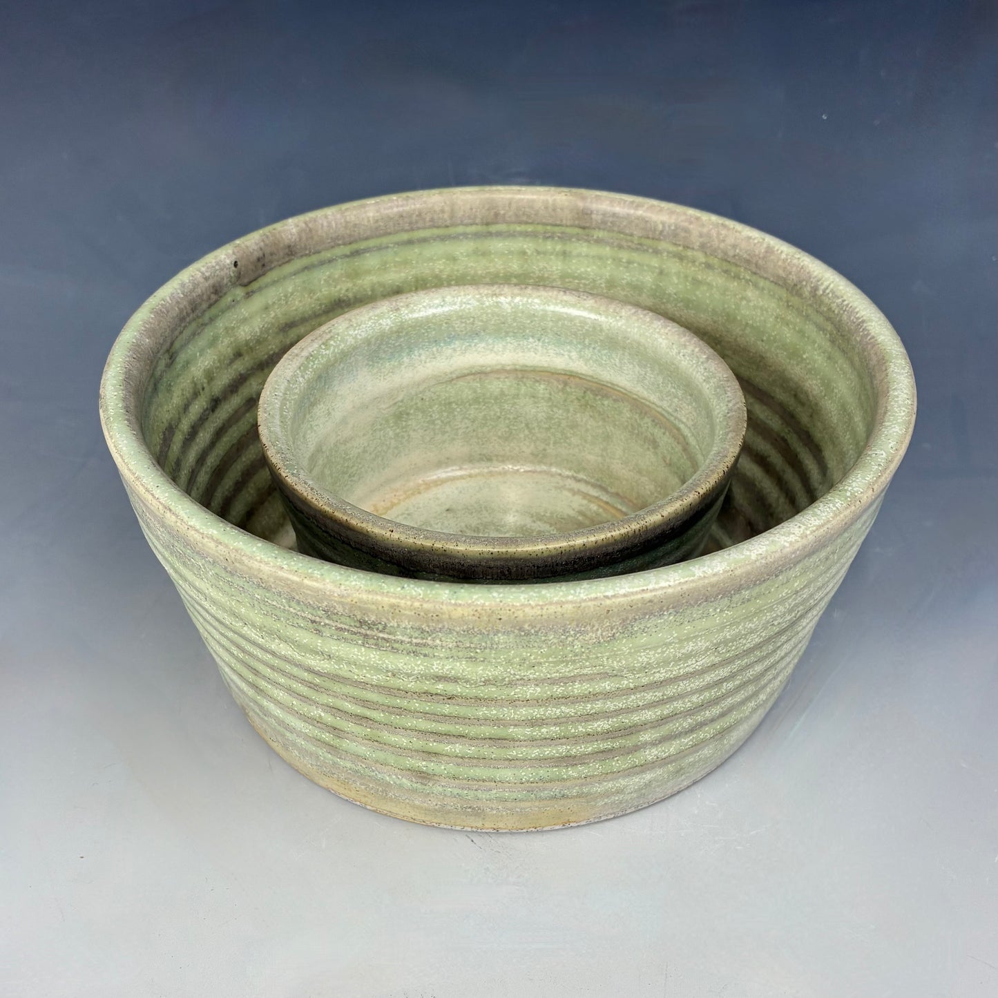 Two green ceramic bowls stacked on a gray background
