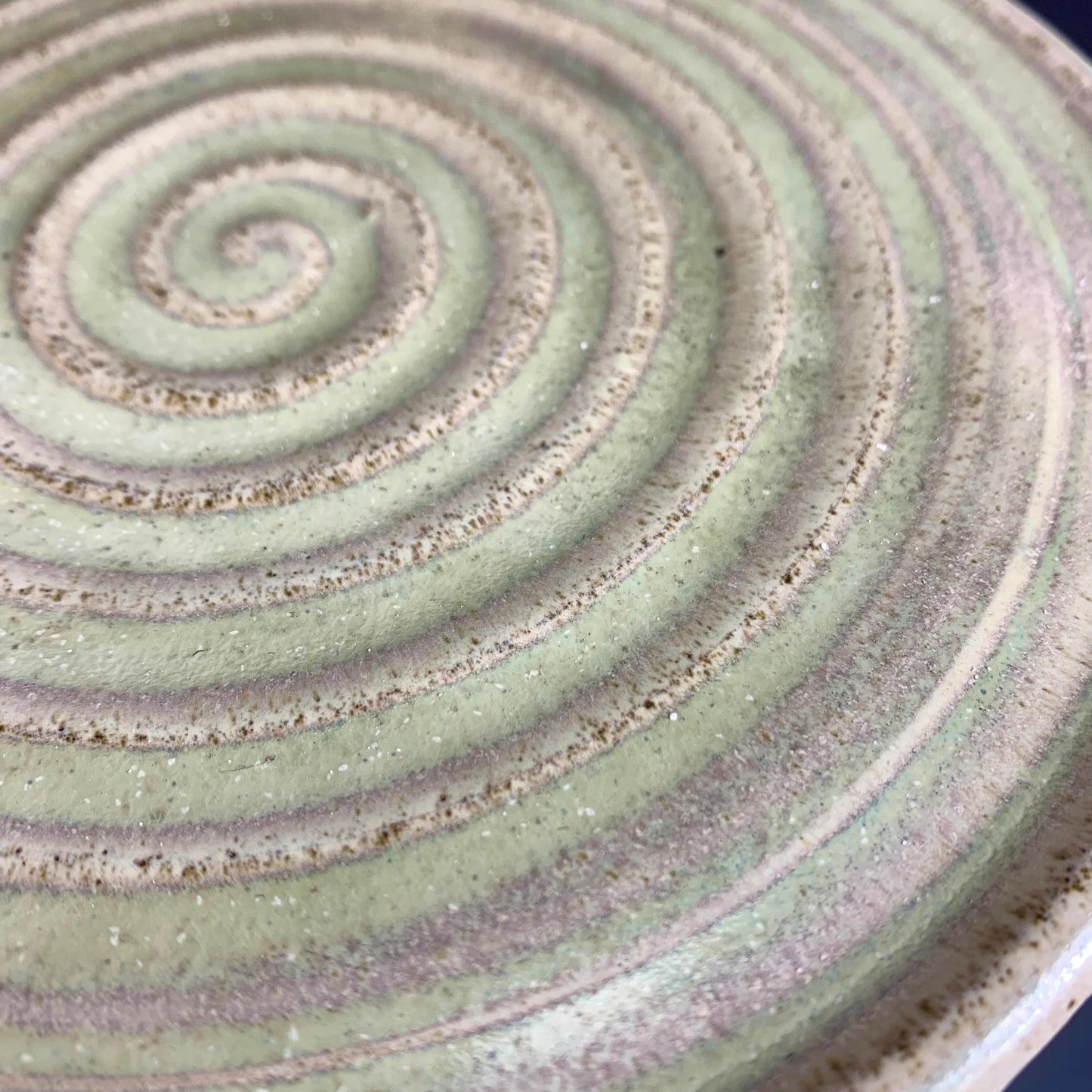 Detail of glaze color variation of Green and Gray ceramic storage container on dark background, lid on