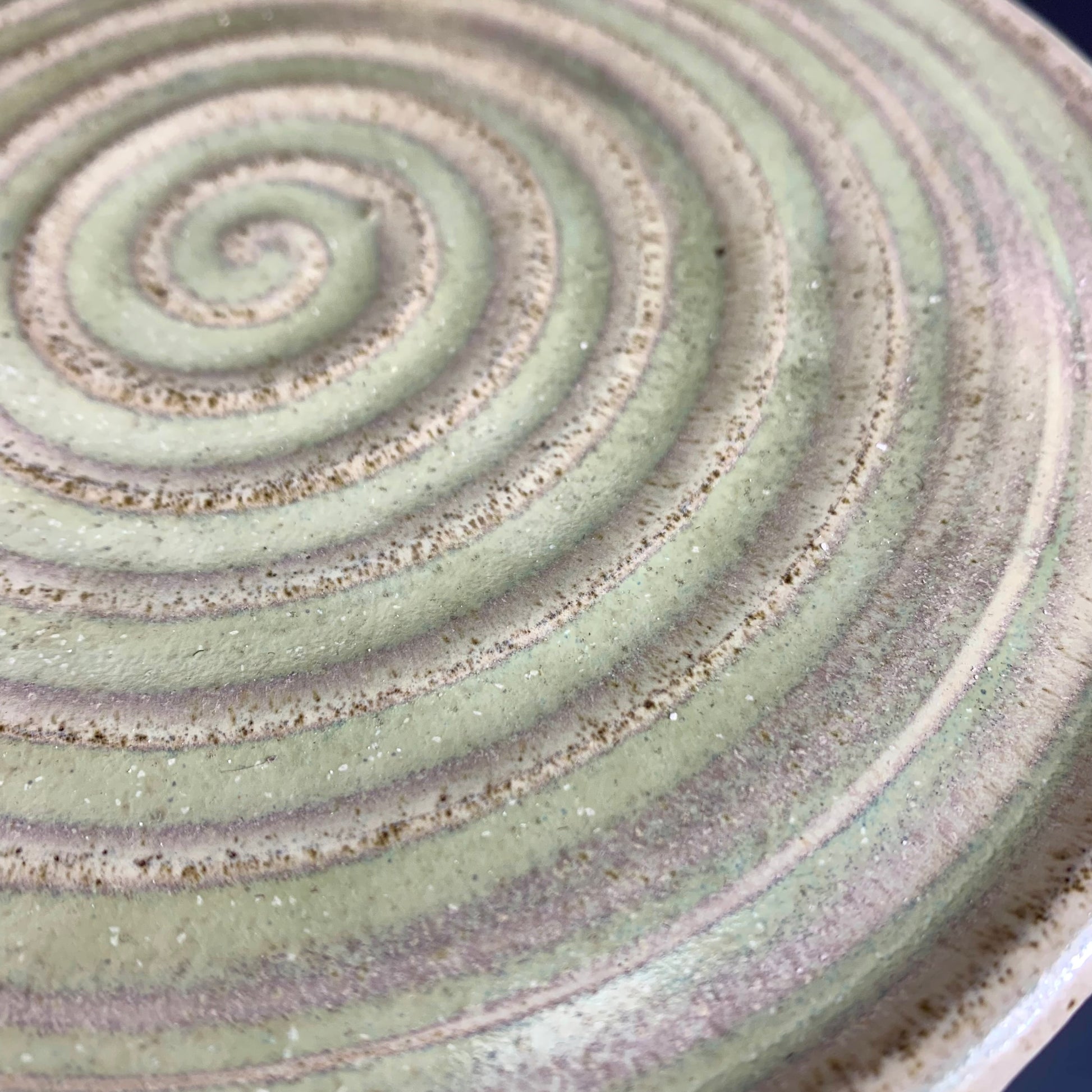 Detail of glaze color variation of  Green and Gray ceramic storage container on dark background, lid on