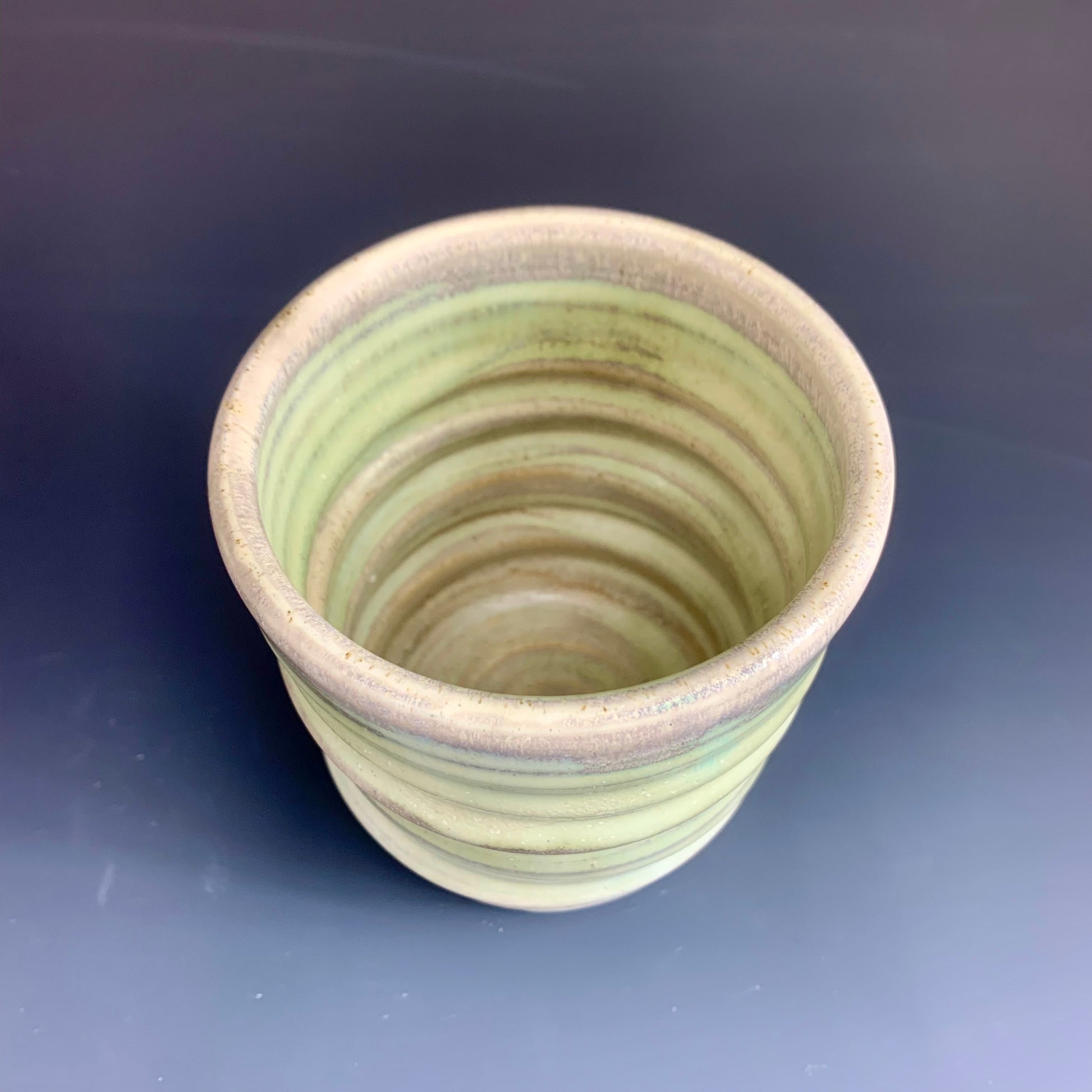 Above View of Green and Gray Wheel thrown cup on dark  background