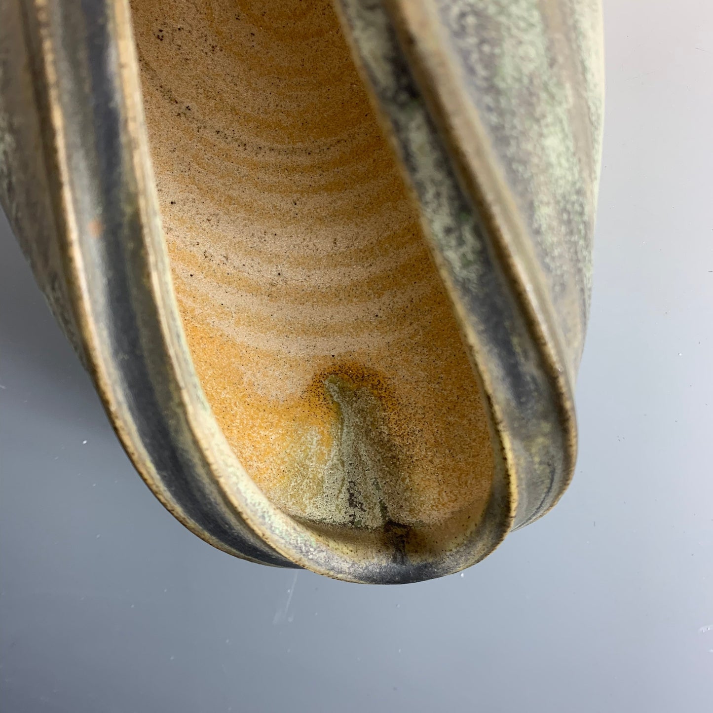 Detail of glaze drip of handmade yellow and green watering can for plants
