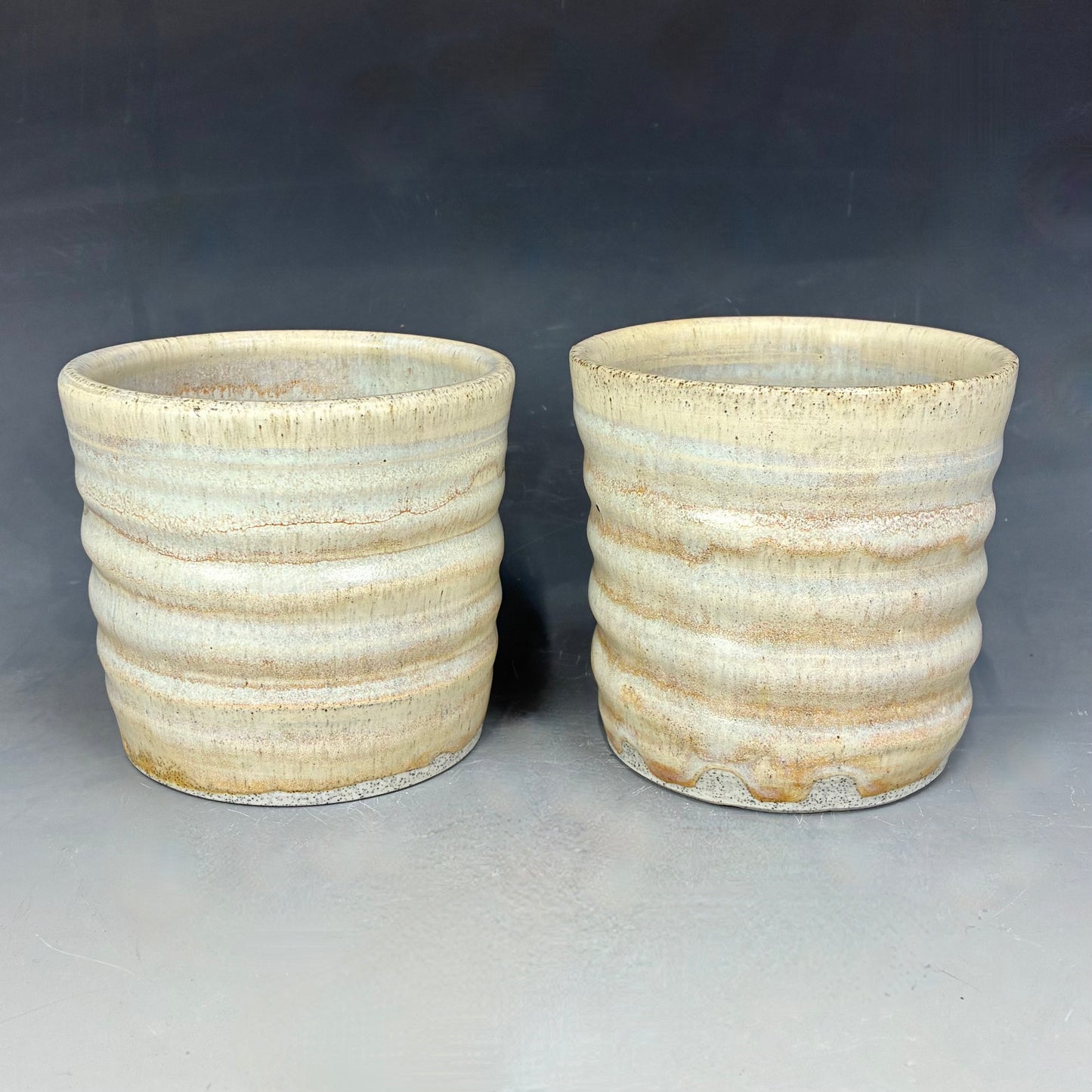 Two ceramic pots with ribbed texture on a gray background