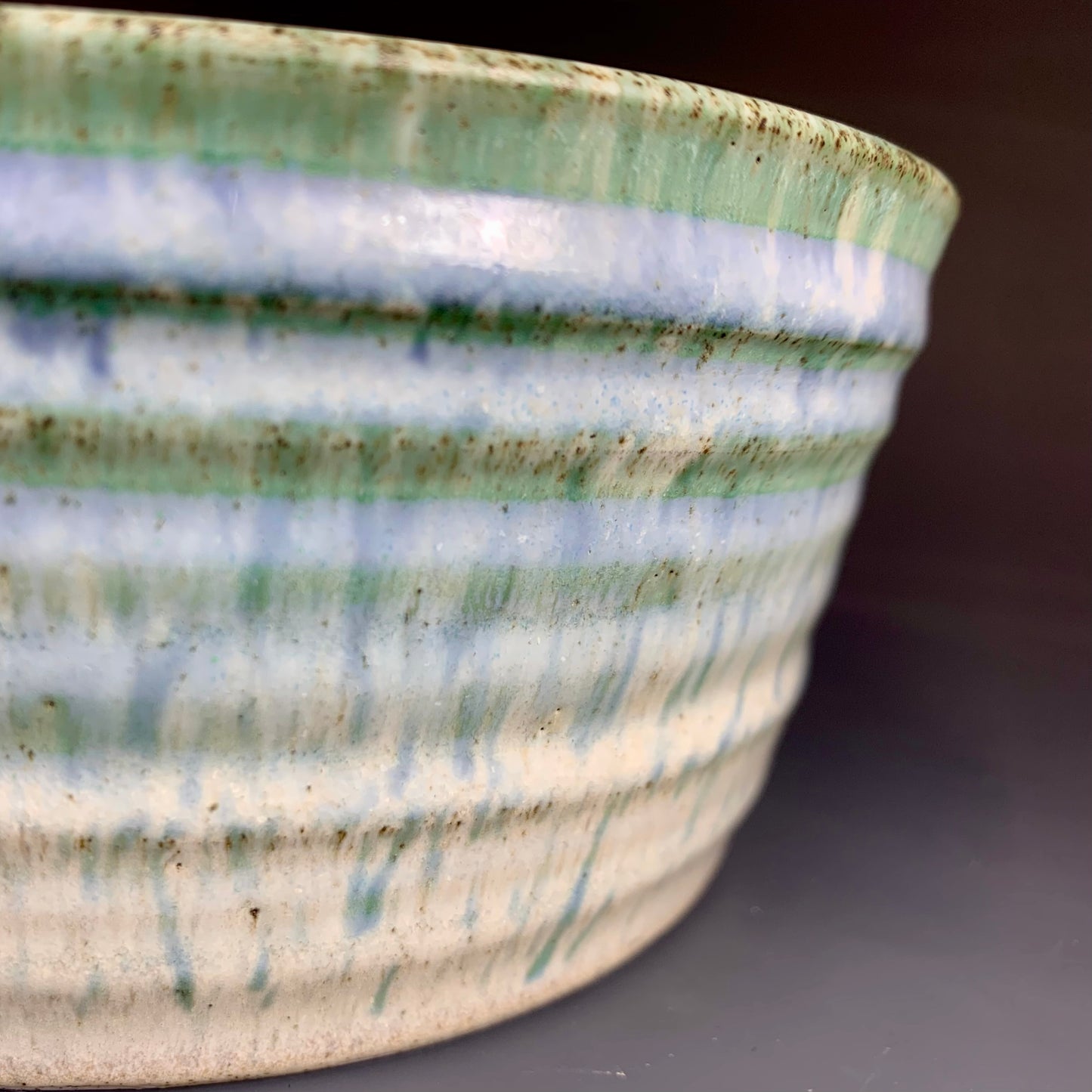 Detail of glaze color variation of Blue and White Wheel thrown bowl on dark background