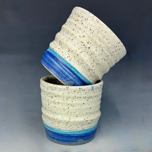Two ceramic pots with blue and white speckled design on a gray background