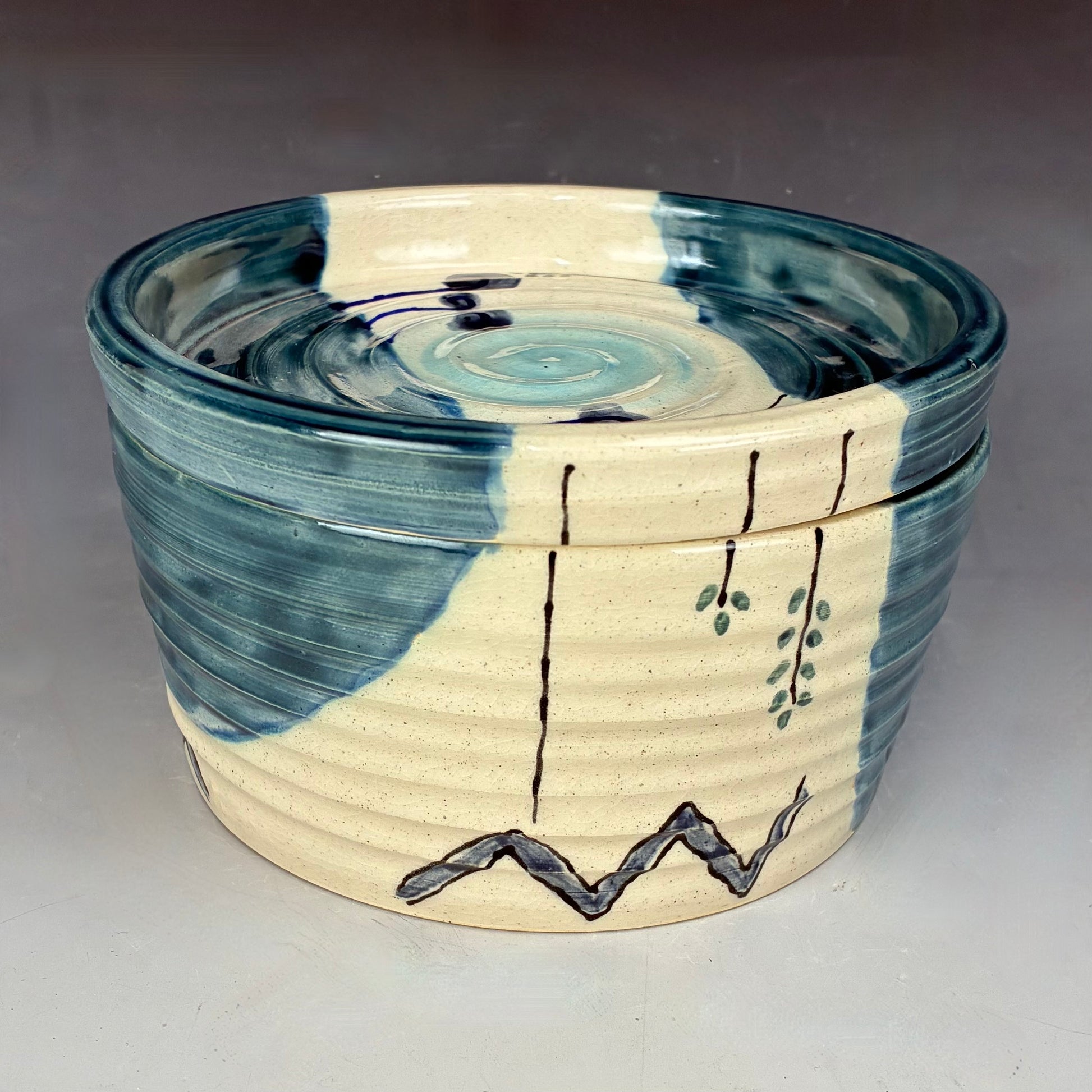 Ceramic container with blue and beige design on a gray background
