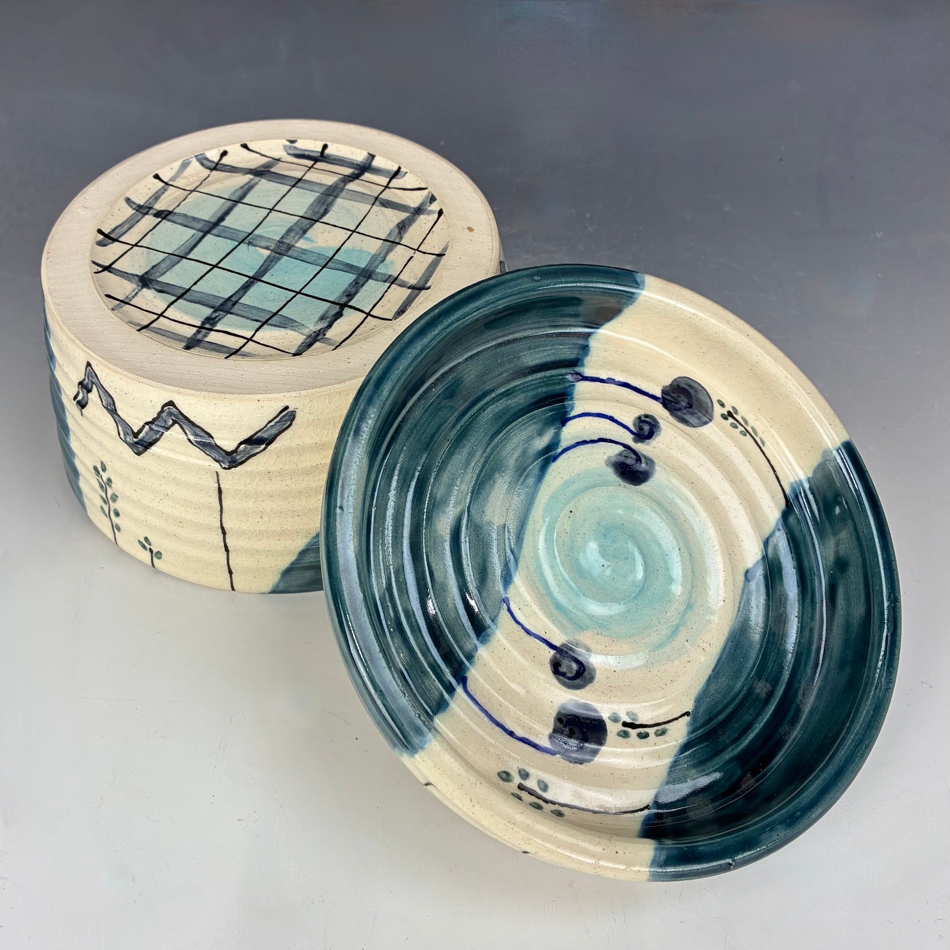Ceramic container with lid featuring blue and white patterns on a gray background