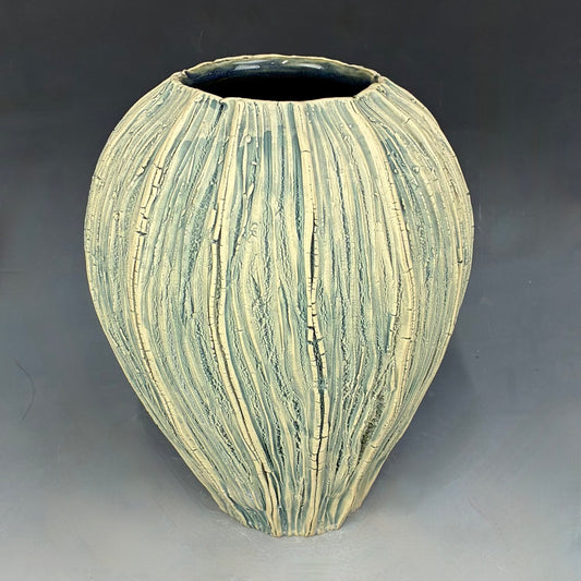 Decorative ceramic vase with striped pattern on a gray background