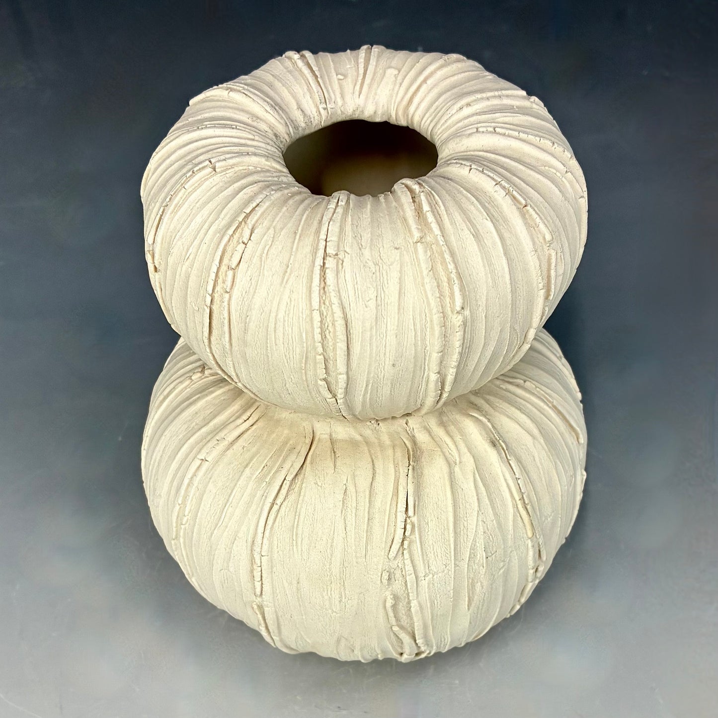  stacked ceramic vase with textured surface on a gradient background