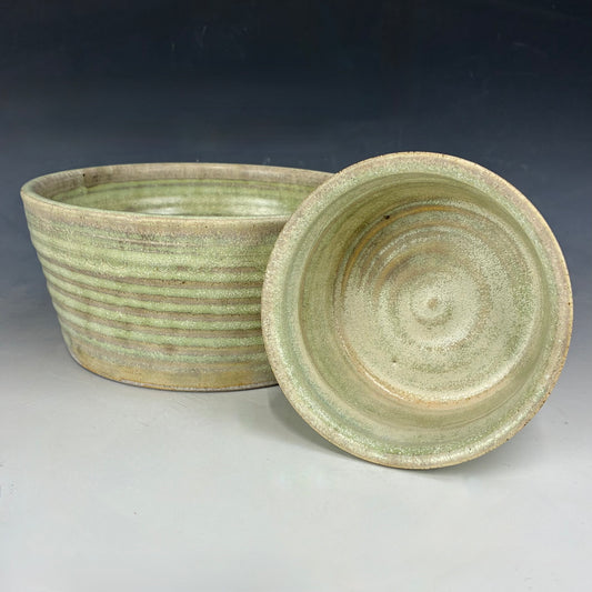 Two green ceramic bowls with a textured surface on a gray background