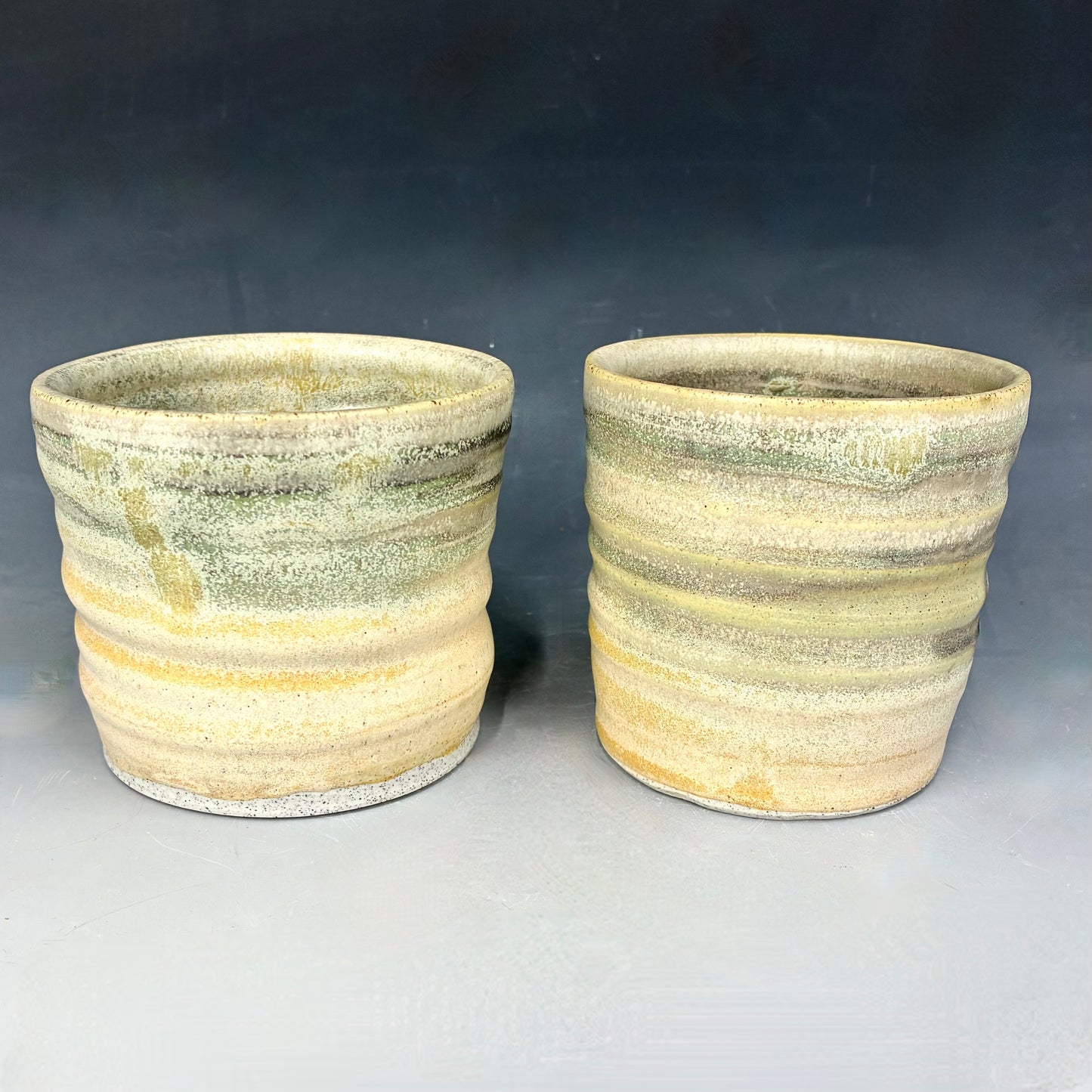 Two ceramic pots with striped design on a gray background