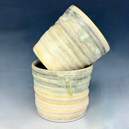 Two ceramic pots with striped patterns on a gradient blue and gray background
