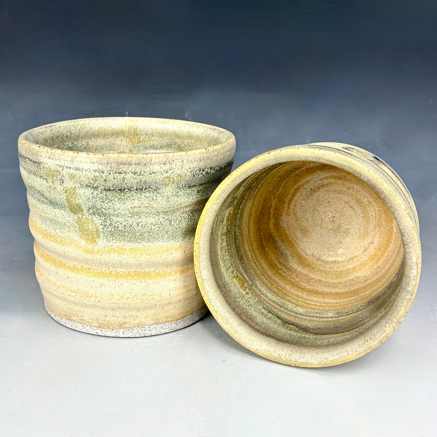 Two ceramic pots with a textured surface on a gradient background
