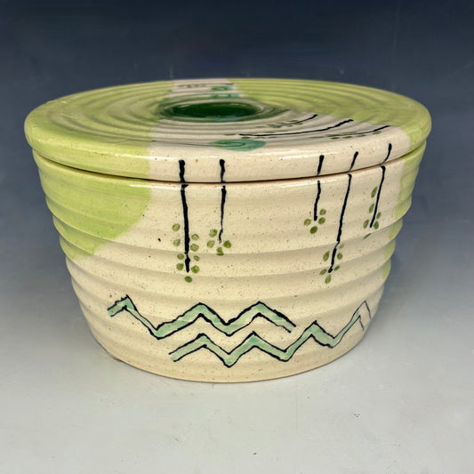 Ceramic container with green and black patterns on a gray background