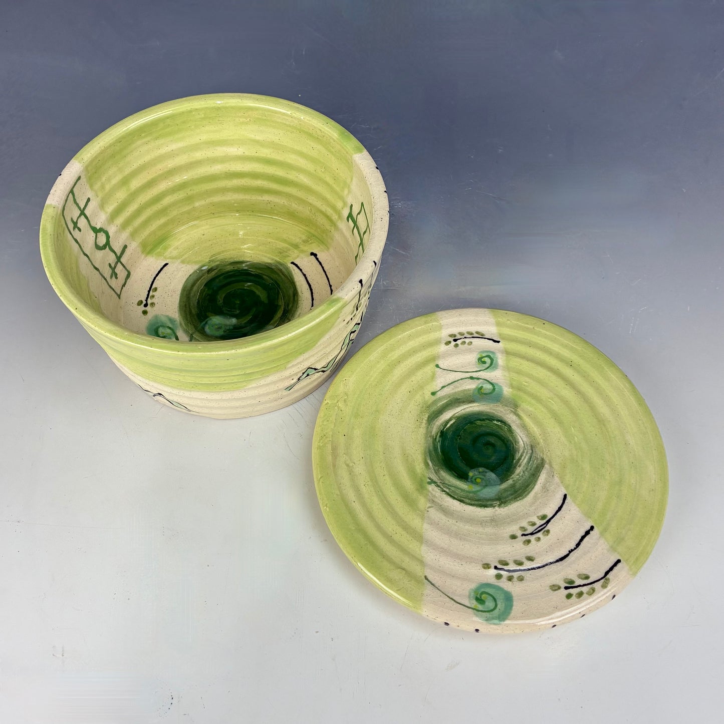 Two green ceramic containers with a textured surface on a gray background