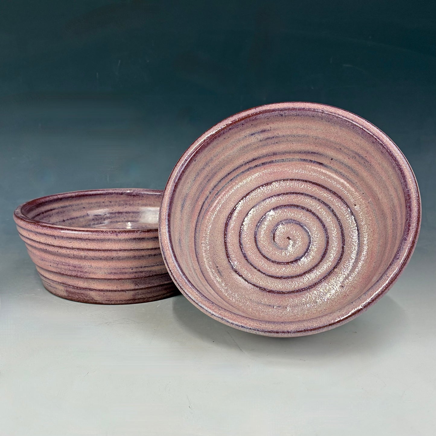 Two ceramic bowls with spiral patterns on a gradient background