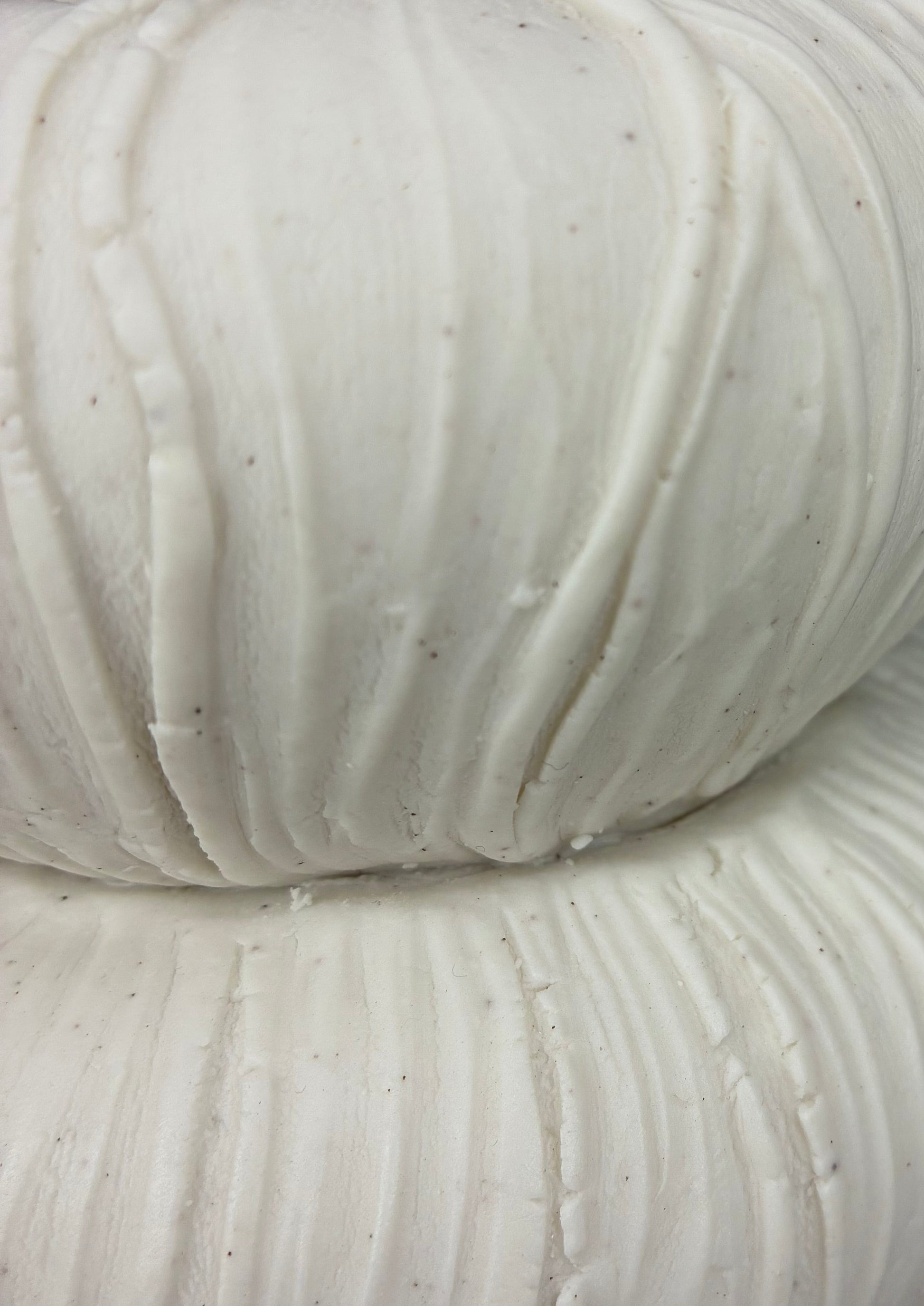 detail of white ceramic pot with textured surfaces on a dark background
