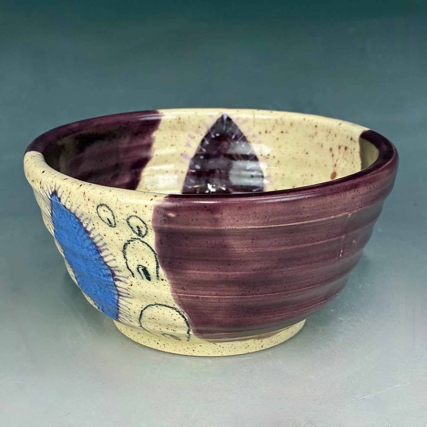 Ceramic bowl with purple and blue patterns on a gray background