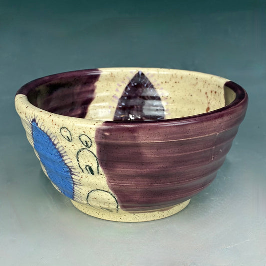 Ceramic bowl with purple and blue patterns on a gray background