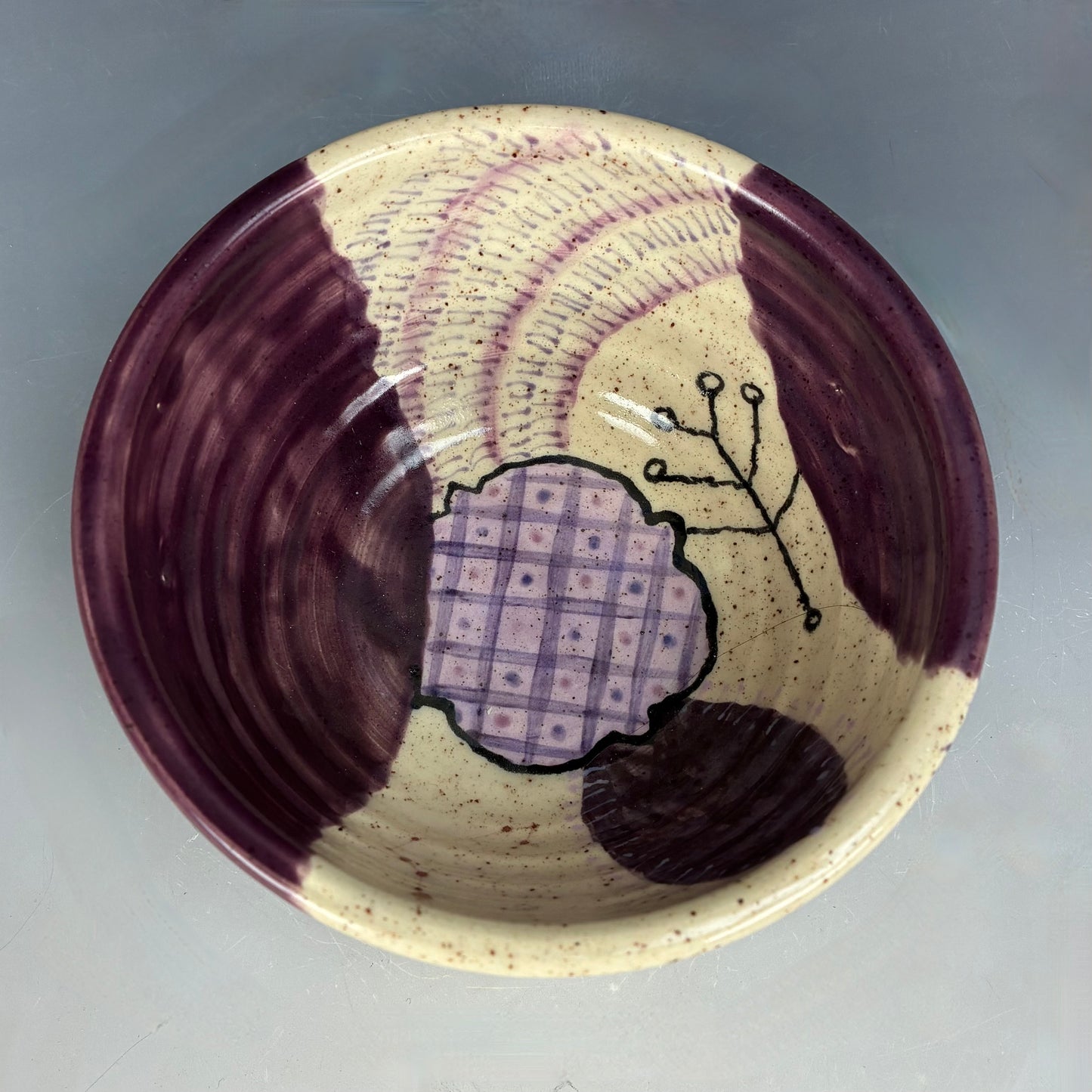 Ceramic bowl with purple and beige design on a gray background