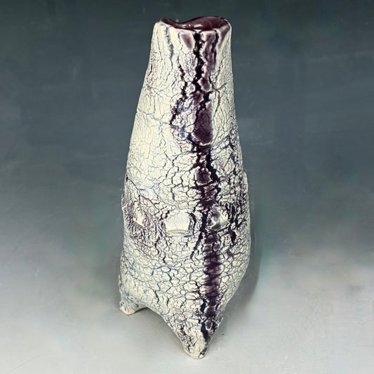 Ceramic vase with textured surface and purple accents on a gray background