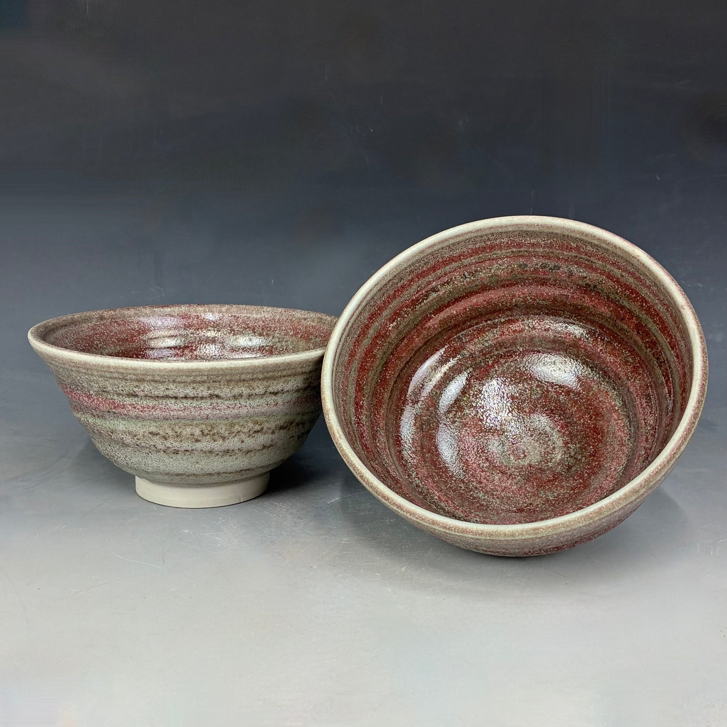 Two ceramic bowls with a speckled glaze on a gray background