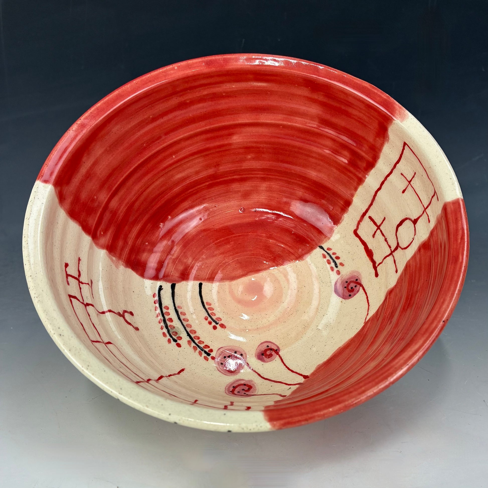 Ceramic bowl with red and beige design on a dark background