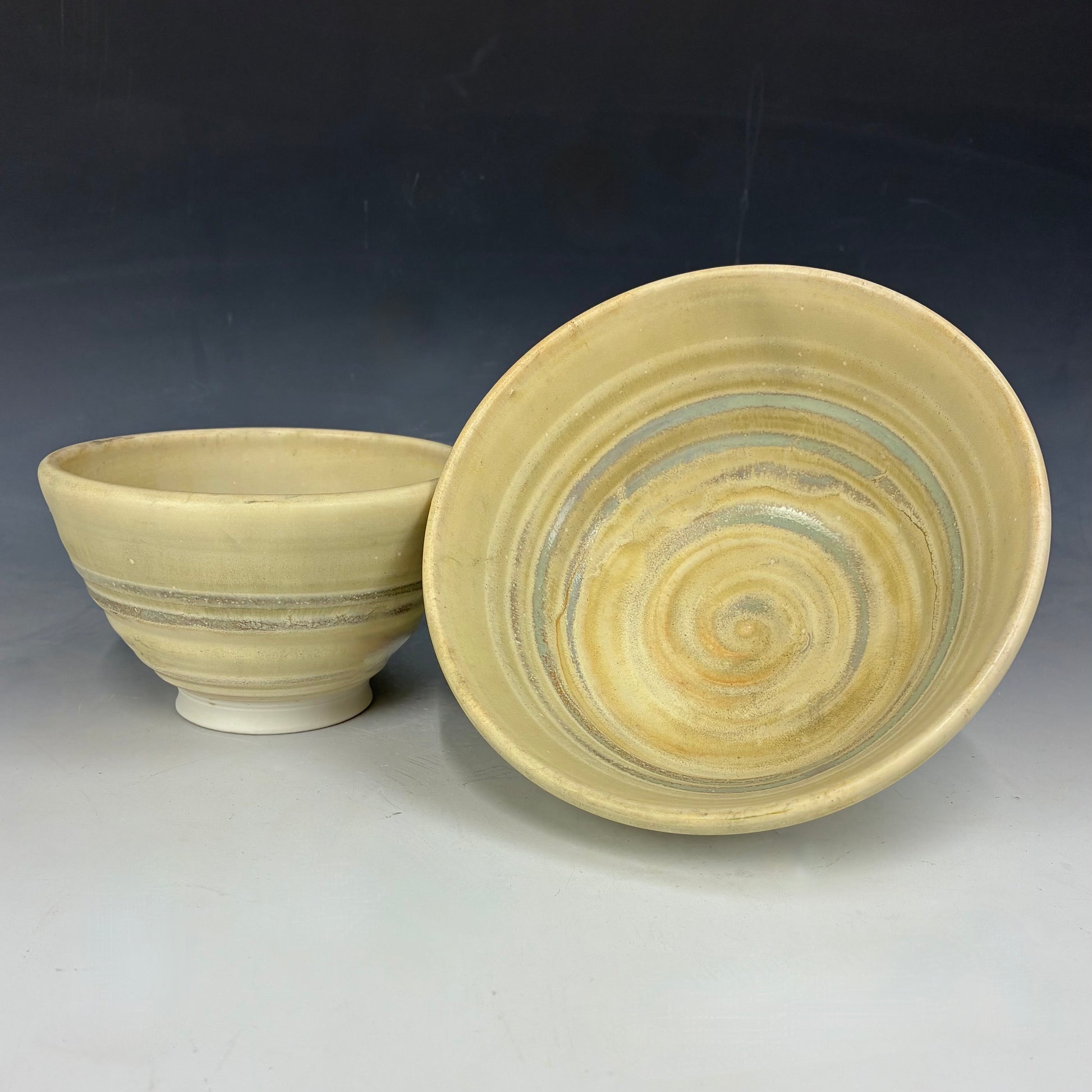 Two ceramic bowls with a swirling pattern on a dark background