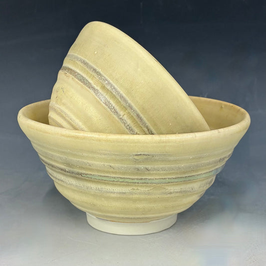 Two ceramic bowls with striped patterns on a gray background