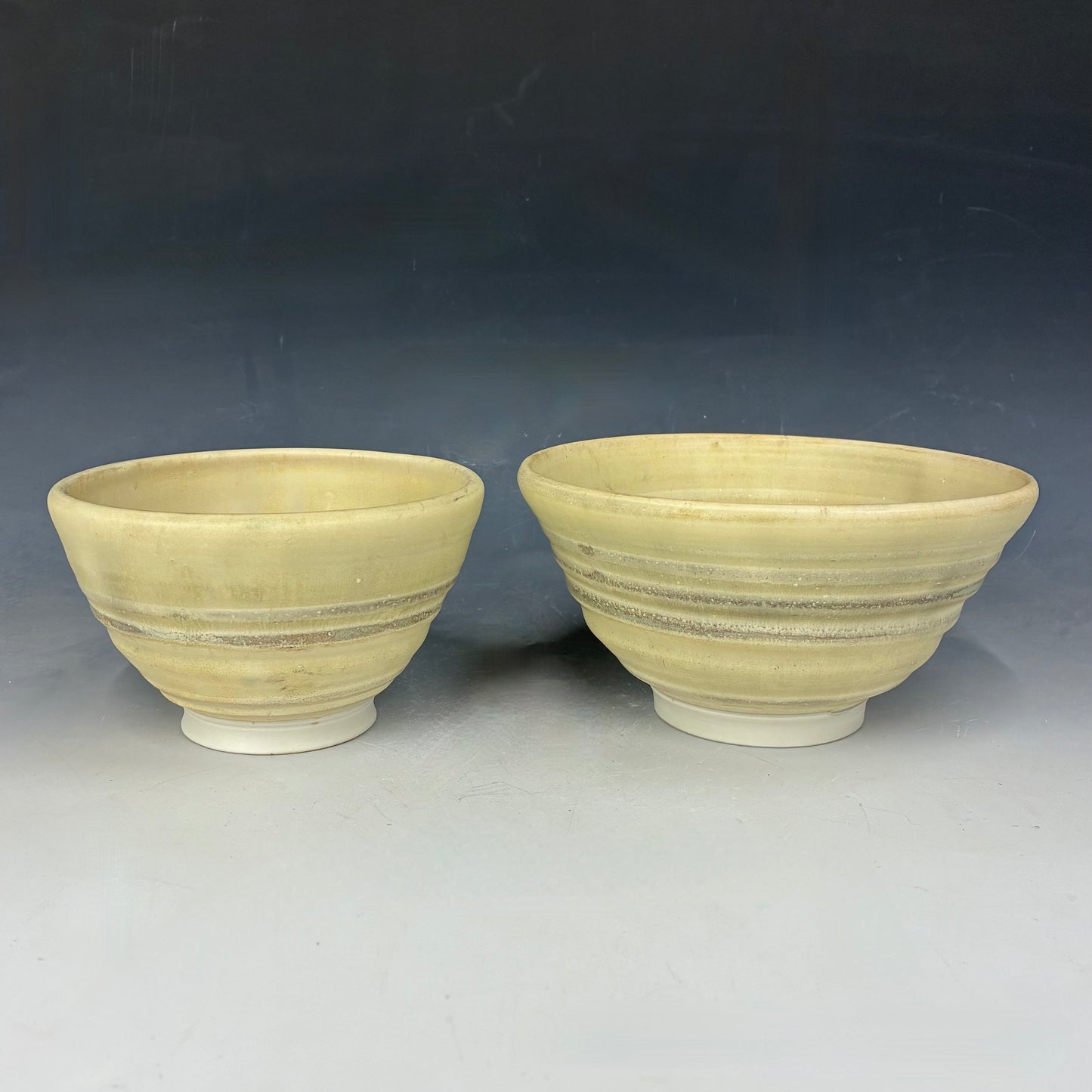 Two ceramic bowls with striped design on a gray background