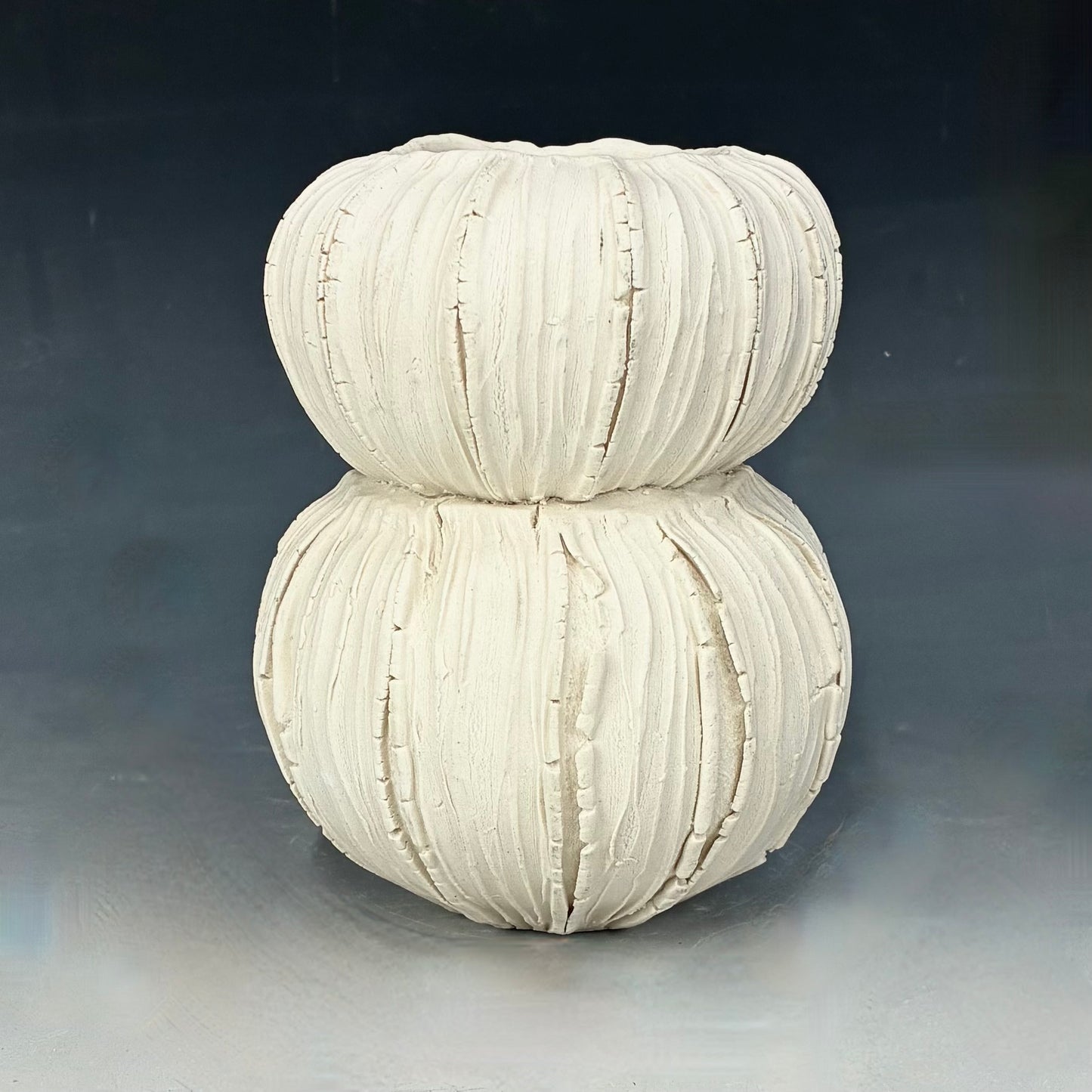 White ceramic vase with ribbed texture on a gray background