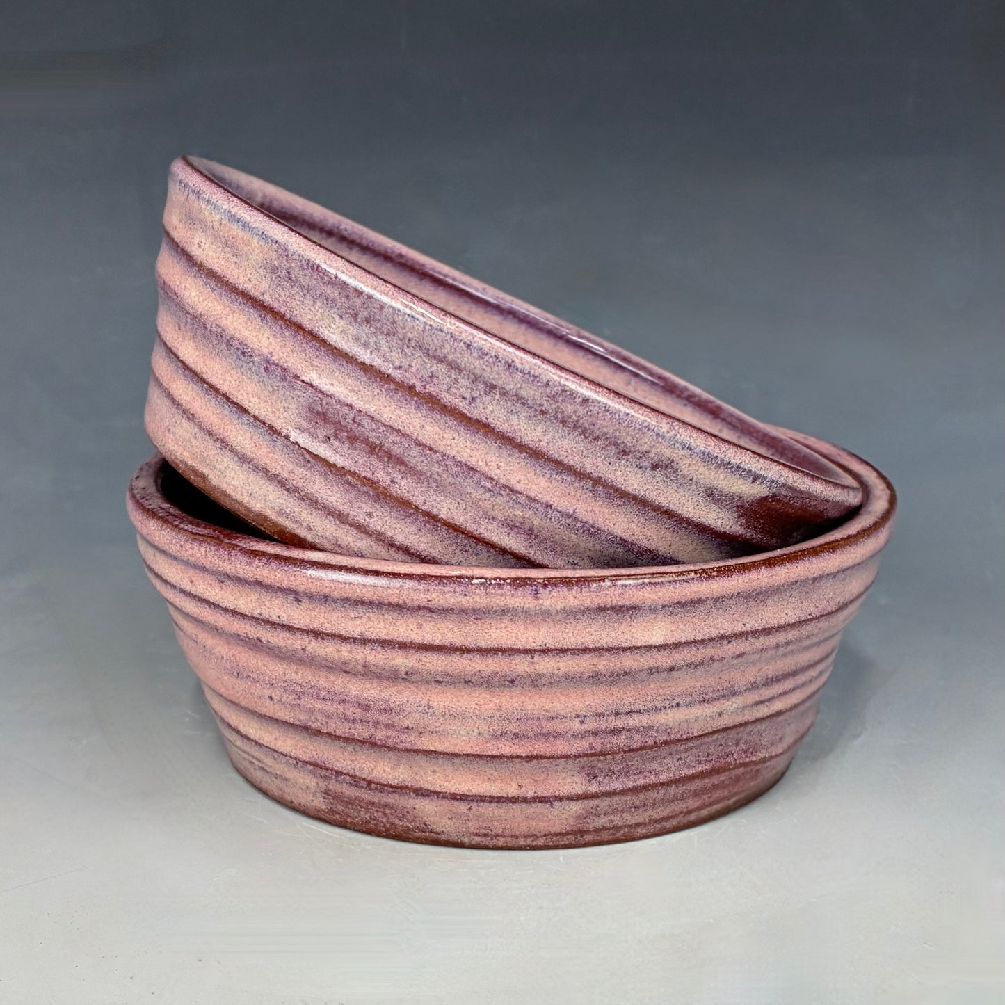 Two ceramic bowls with a striped pattern on a gray background