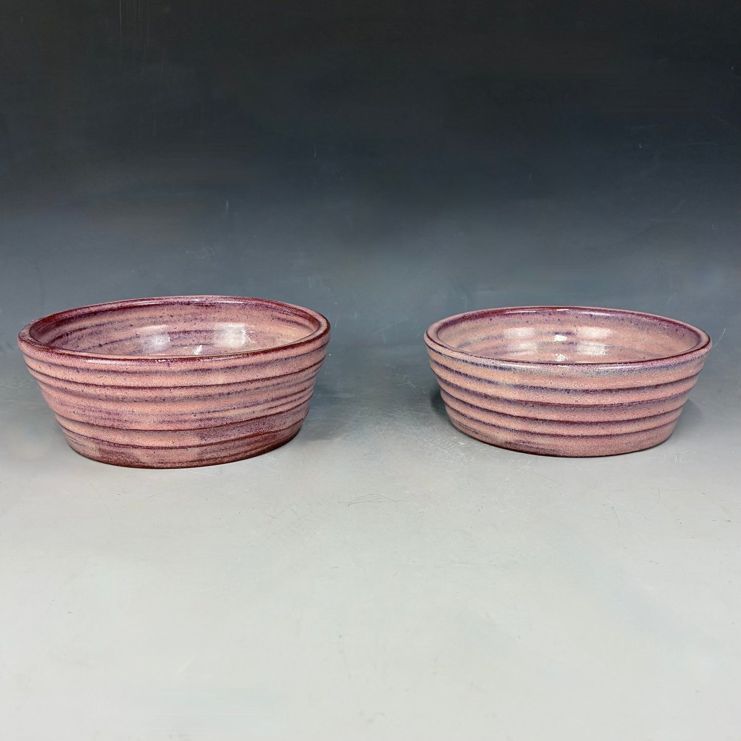 Two pink ceramic bowls on a gray background