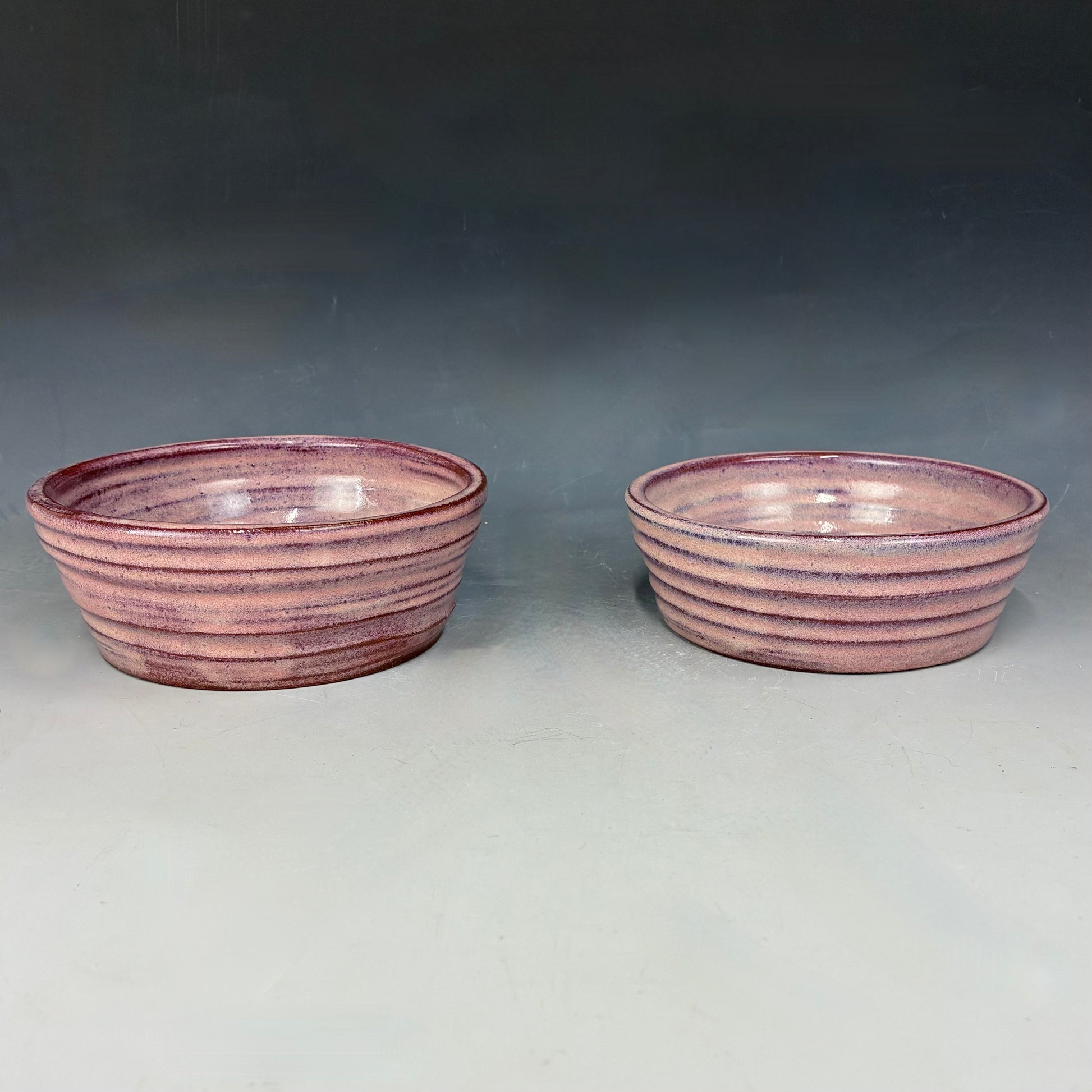 Two pink ceramic bowls on a gray background