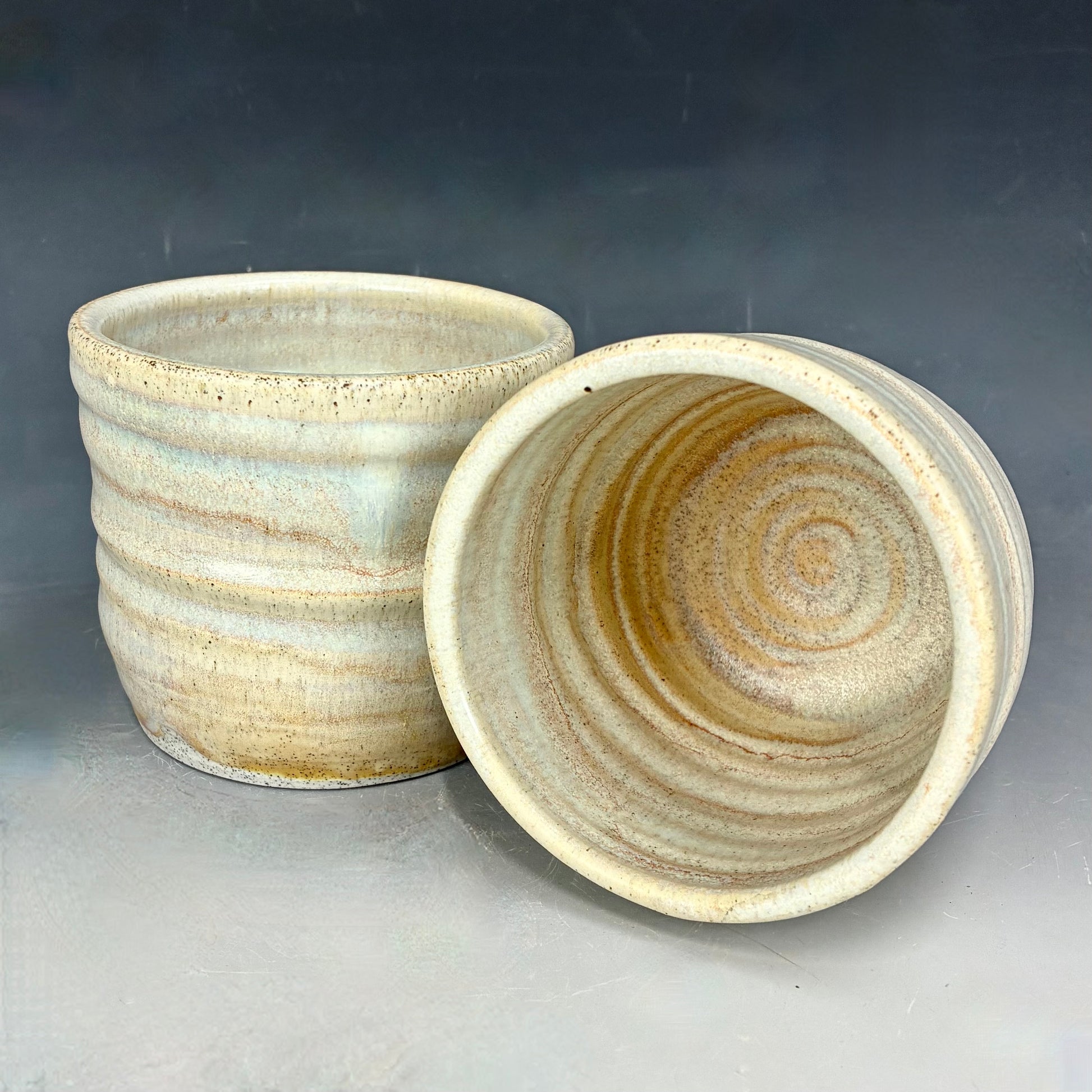 Two ceramic pots with textured surfaces on a gray background