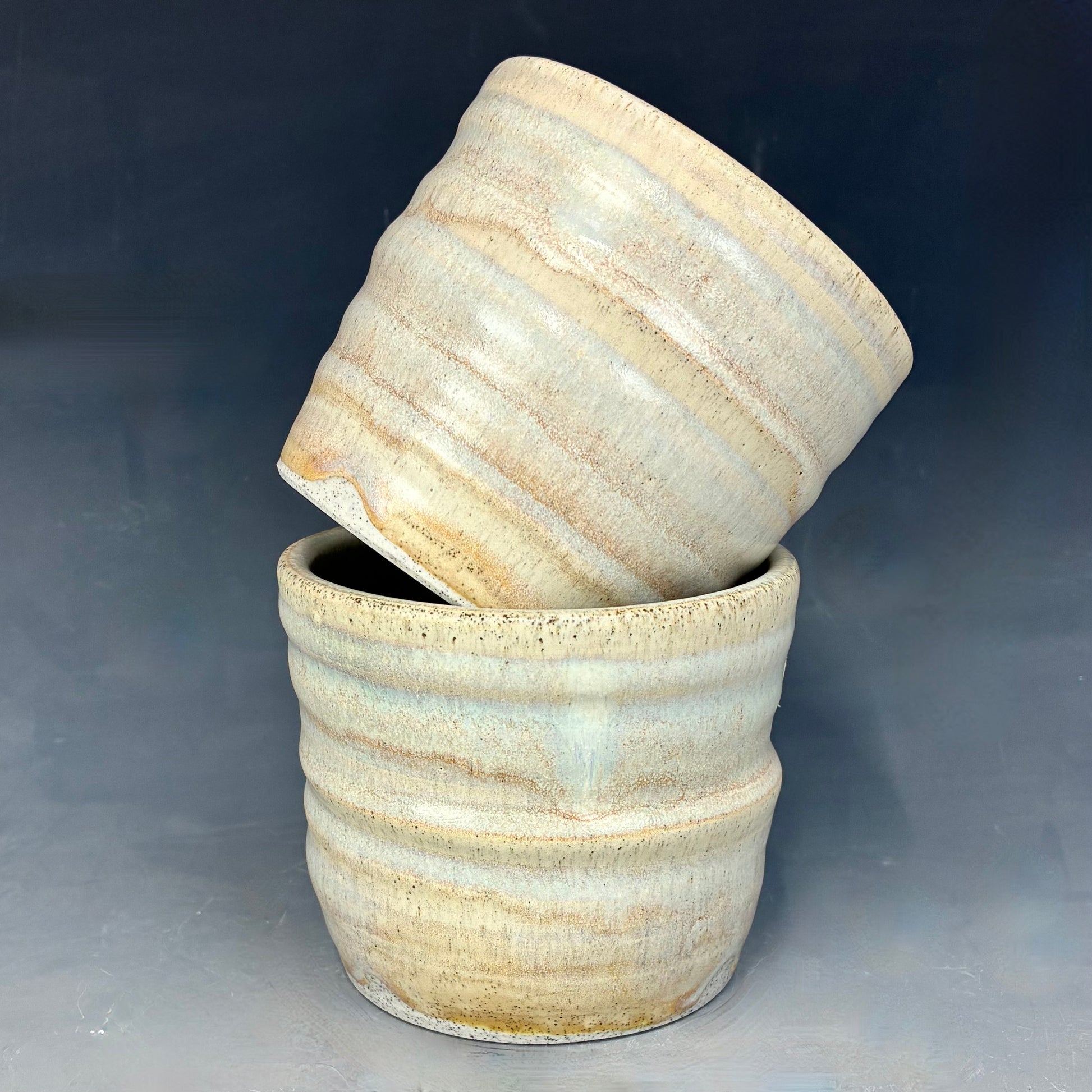 Two ceramic pots with a textured surface on a gray background