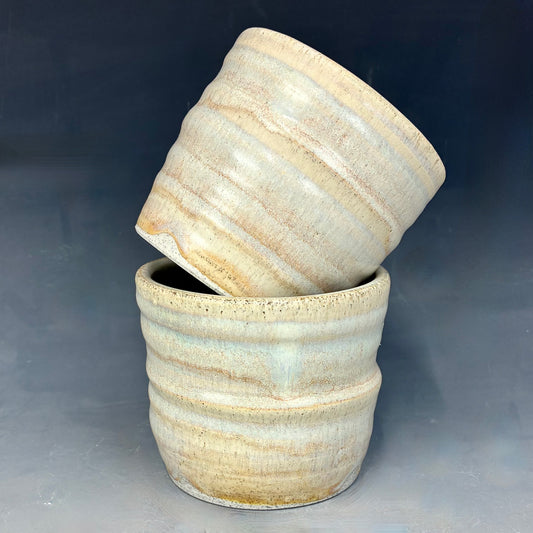 Two ceramic pots with a textured surface on a gray background