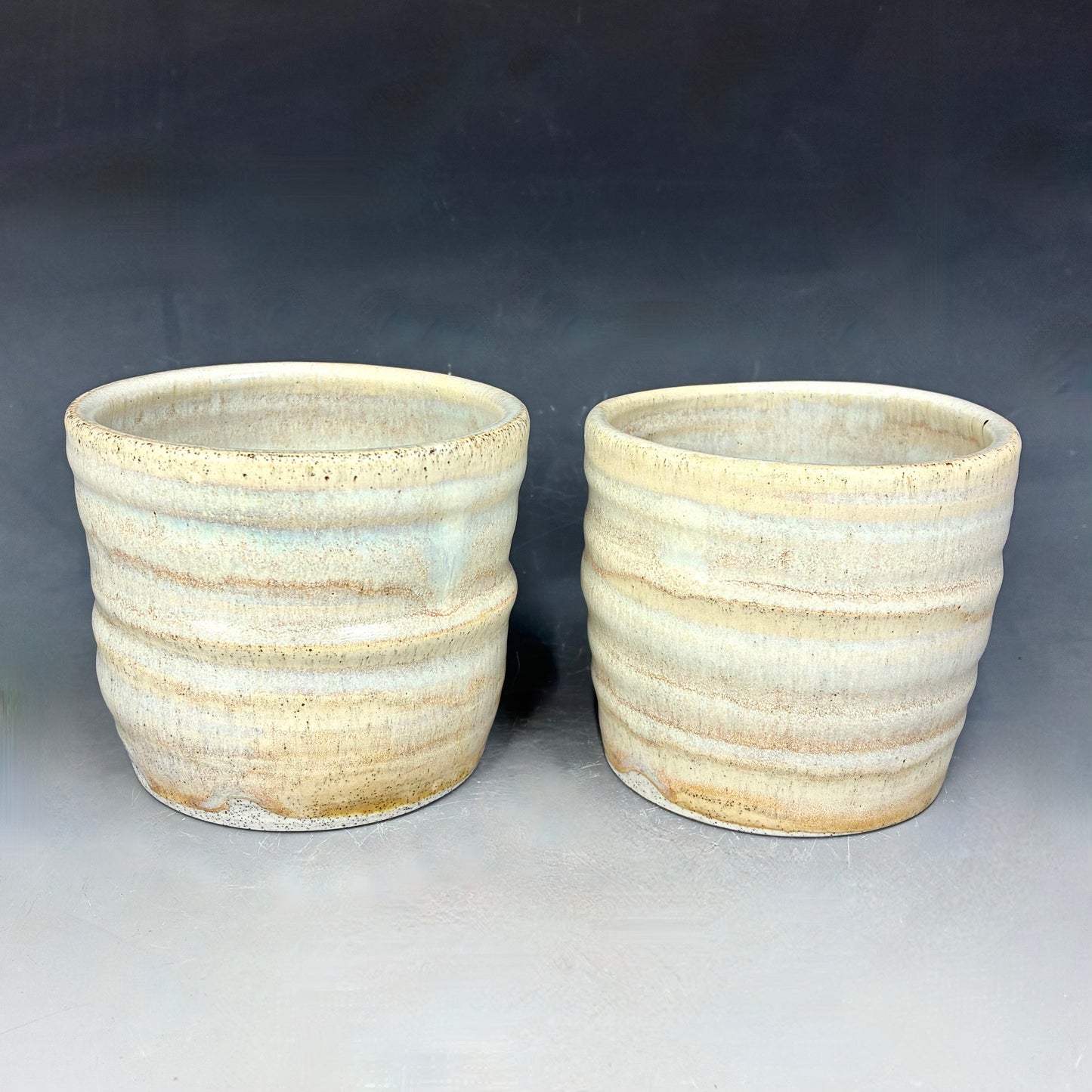 Two ceramic pots with textured surface on a gray background