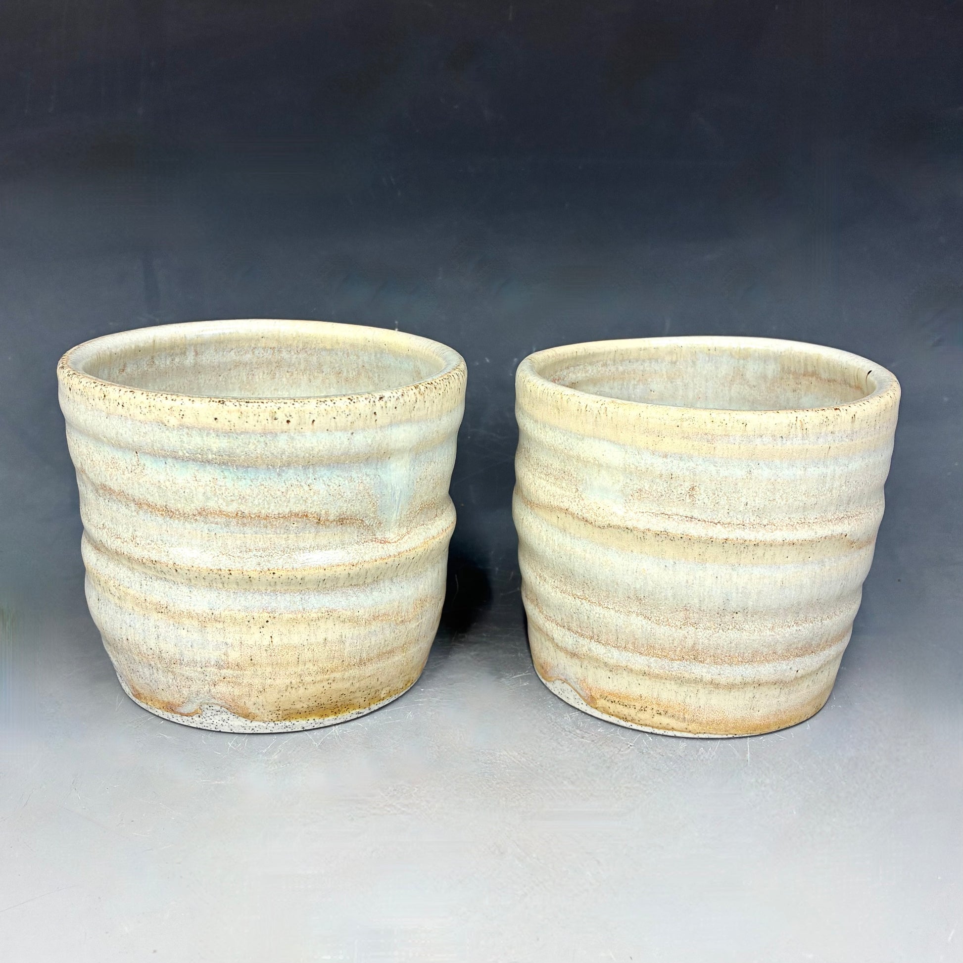Two ceramic pots with textured surface on a gray background