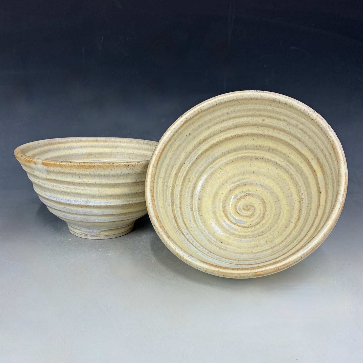 Two ceramic bowls with spiral patterns on a gradient background