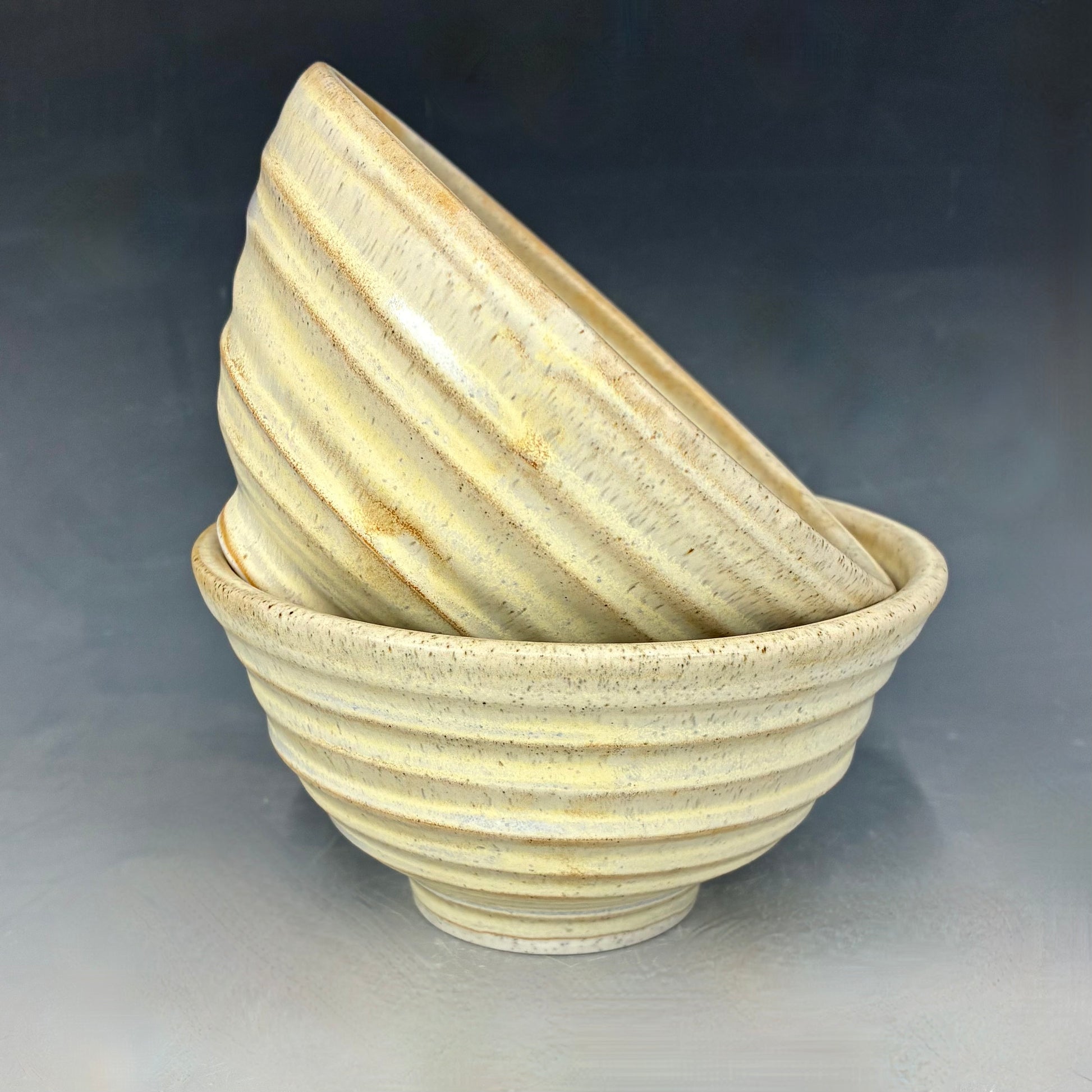 Stack of ceramic bowls with ribbed texture on a gray background